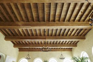 A ceiling with wooden beams and a chandelier.