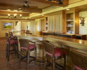 A bar with several chairs and stools in it.