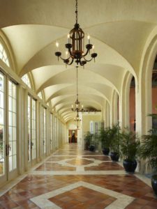 A long hallway with potted plants and a chandelier.