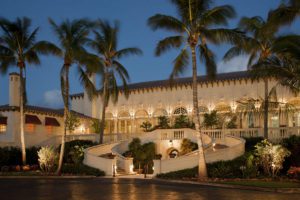 A building with palm trees and lights on the side.