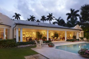 A large pool with chairs around it and palm trees in the background.